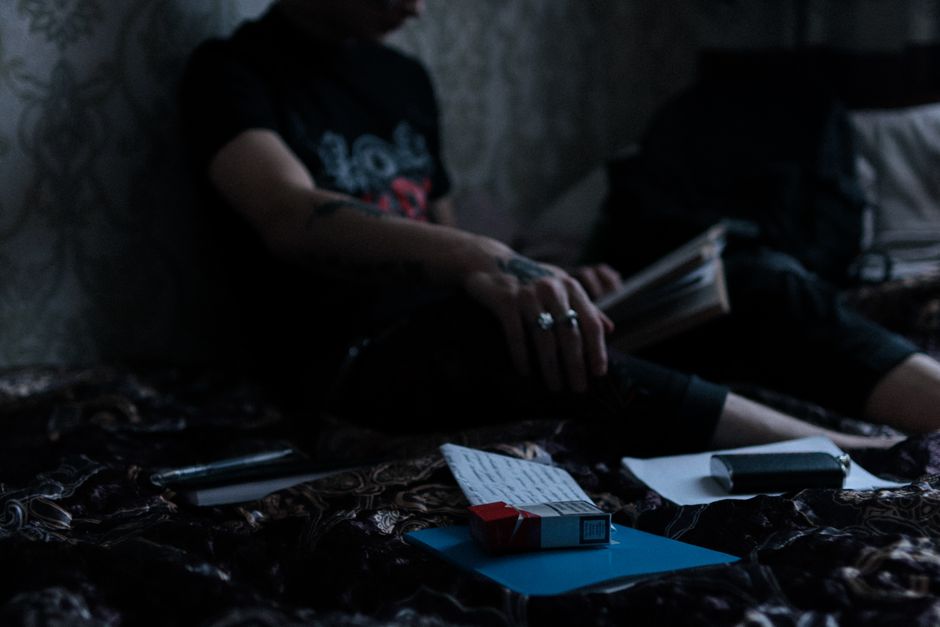 A man in a dimly lit room with cigarettes and a book adds a sense of rebellion and mystery.