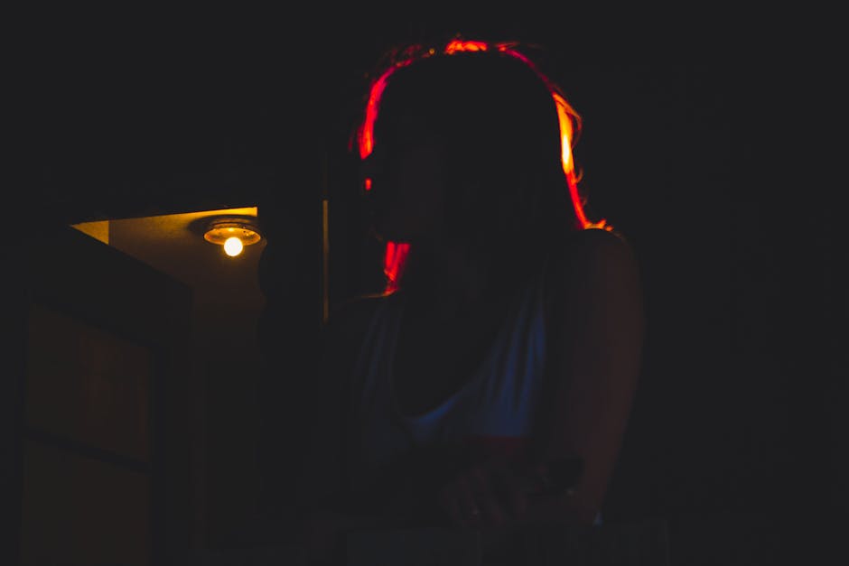 A dramatic silhouette of a woman with vibrant lighting in a dark environment.