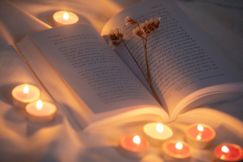 Open book surrounded by candles and dried flowers creating a warm, inviting atmosphere.