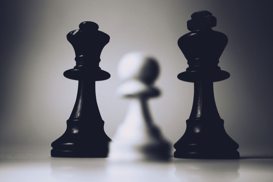 Close-up artistic photo of chess king and pawn in dramatic lighting.