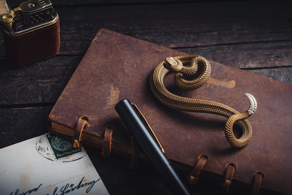 A stylish composition with a vintage journal, snake figurine, pen, and lighter on a rustic wooden desk.
