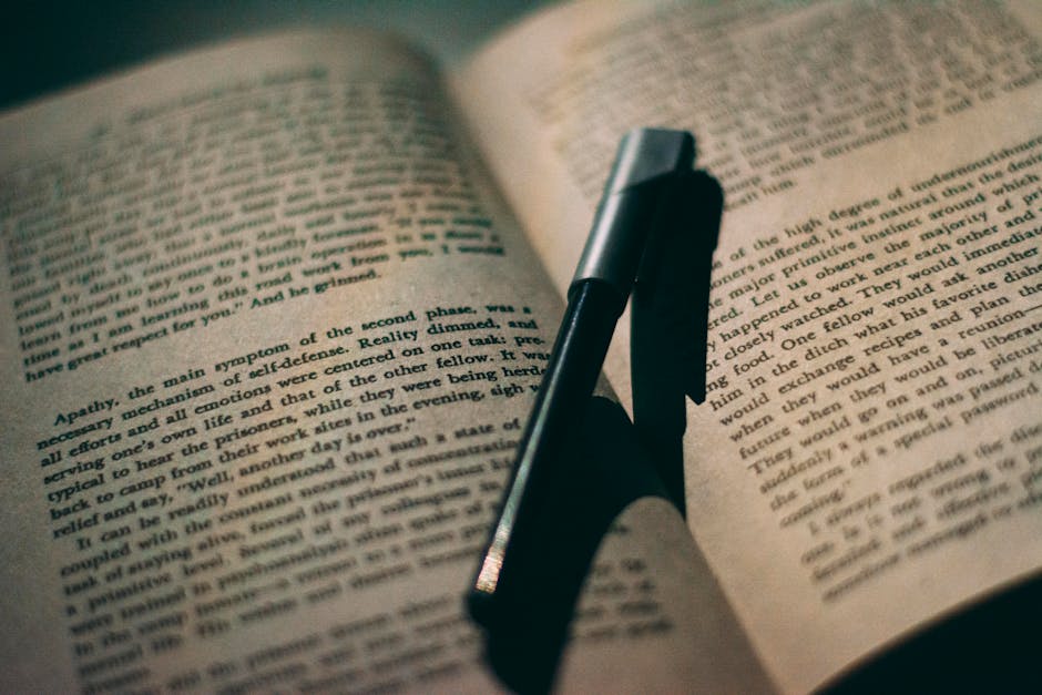 Close-up of a ballpoint pen resting between the pages of an open book, perfect for education or reading themes.