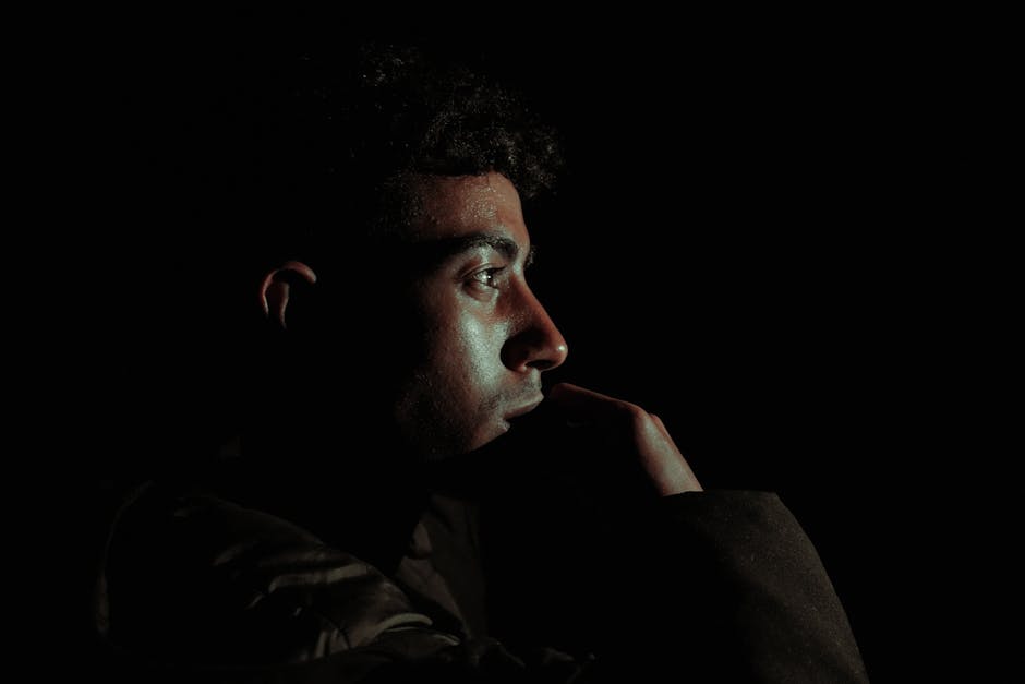 Close-up profile of a man in dramatic lighting, creating a moody atmosphere.