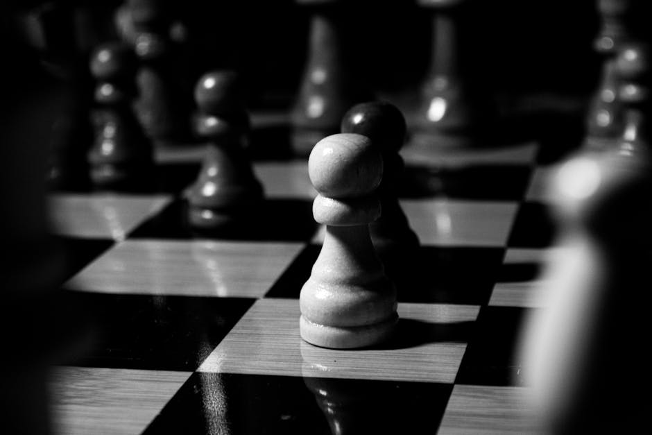 Dramatic black and white photo of chess pieces focused on a pawn, depicting strategic gameplay.