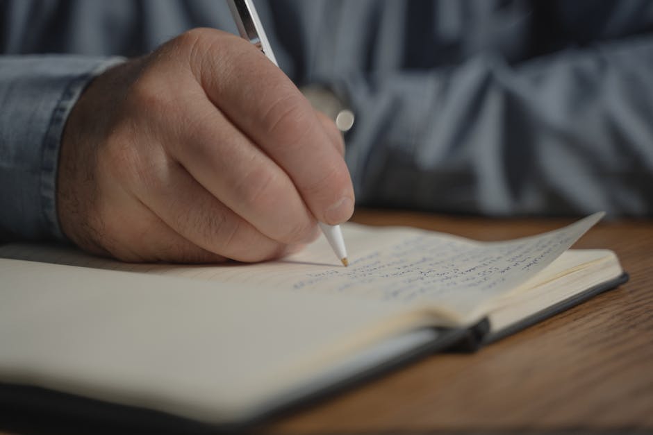 A close-up image of a hand writing with a pen in a notebook, creating a personal diary entry.