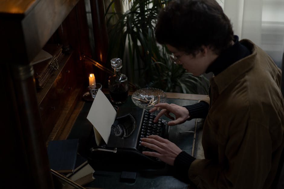 A man in a brown jacket types on a vintage typewriter by candlelight, creating a classic writing atmosphere.